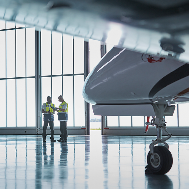 Two Aircraft Mechanics in Hangar with Jet