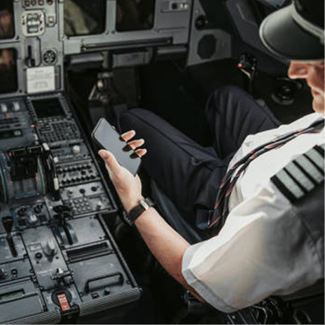 Pilot seated in flight deck, looking at cellphone