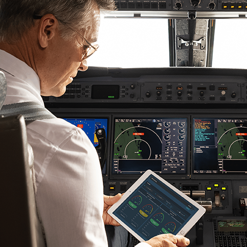 Pilot in flight deck staring at camera, pointing to controls