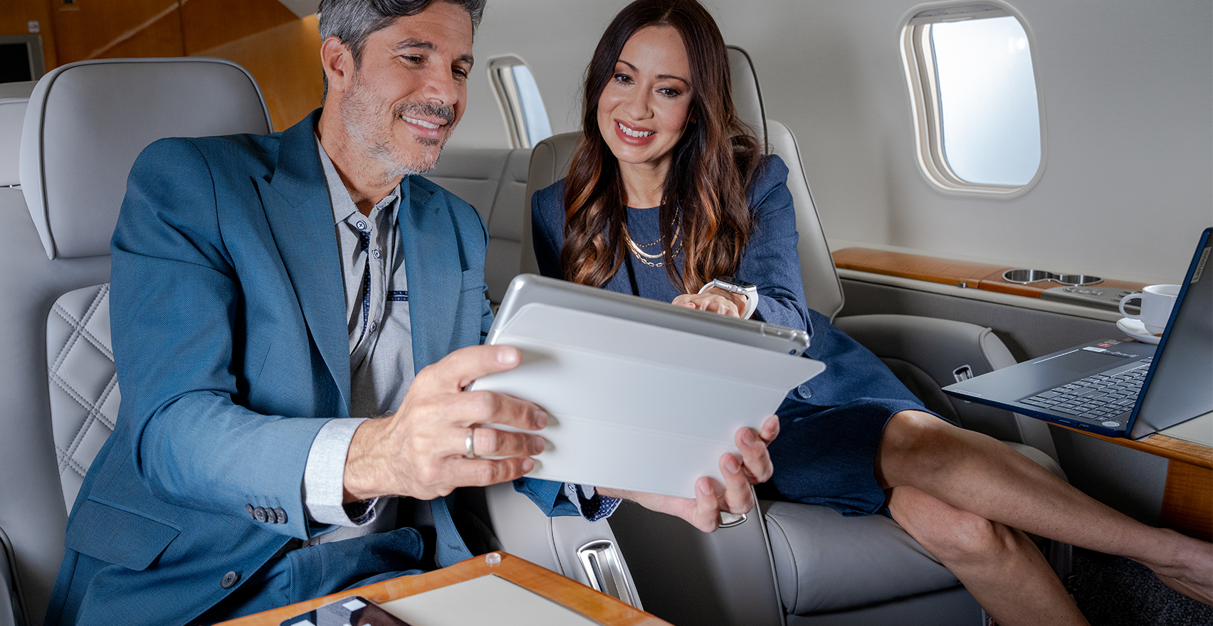 Business man and businesswoman looking at tablet screen in a cabin private jet