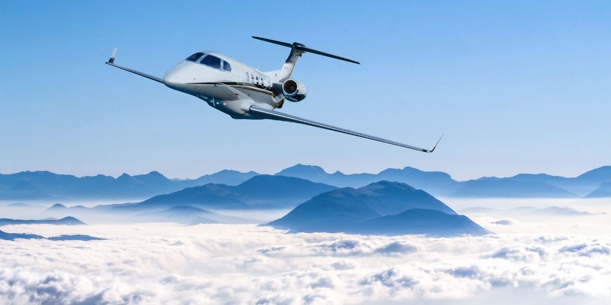 Embraer Phenom 300 flying over mountains peeking out of the clouds Embraer Phenom 300 flying over mountains peeking out of the clouds
